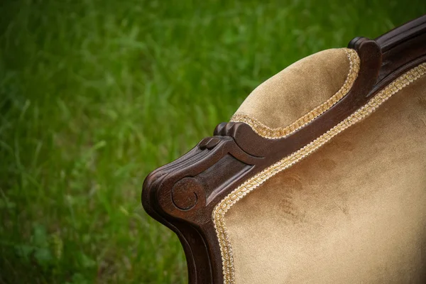 Wooden part of antique furniture against of green grass on blurred background in sunny day outside. Close up shot — Stock Photo, Image