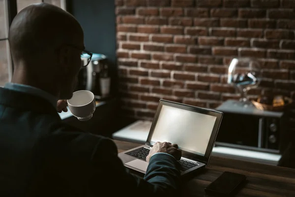 Empresário bebe café trabalhando com computador no centro de negócios. Visão traseira do homem caucasiano digitando no teclado laptop segurando copo em outra mão. Espaço de cópia — Fotografia de Stock