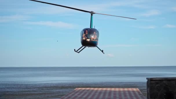 Frontal Robinson - R44 Astro Jet helikopter landde op het dok druppels passagiers. Met draaiende messen. De helikopter ligt op de kade tegen de achtergrond van de zee of de oceaan. Kiev, Oekraïne 09-13-20 — Stockvideo