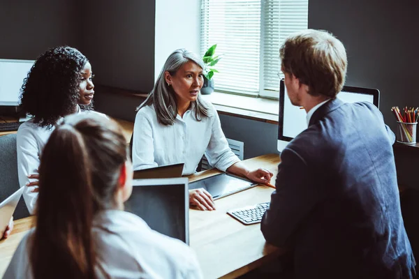 Équipe multiethnique d'affaires avec des ordinateurs à la réunion. Les mains des gens d'affaires touchant l'écran de l'appareil électronique. Image tonique. Vue latérale — Photo