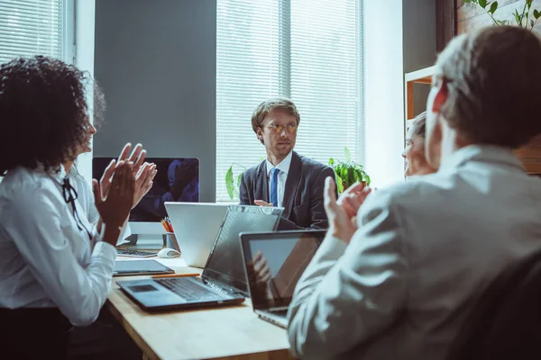 Gente de negocios en ropa de negocios hablando con colegas o socios sentados en la mesa de conferencias, líder masculino discutiendo el trabajo en la reunión de equipo o grupo. Concepto de trabajo en equipo — Foto de Stock