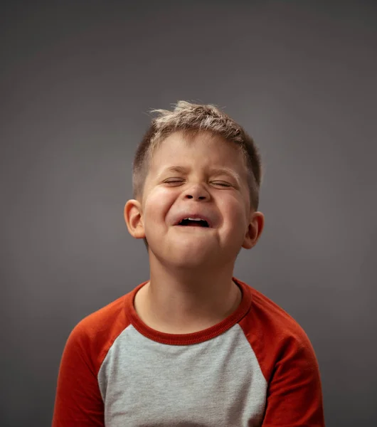 Retrato de un triste niño llorón fingido aislado sobre un fondo gris. Emociones falsas. Emociones humanas, concepto de expresión facial. Expresiones faciales, emociones, sentimientos — Foto de Stock