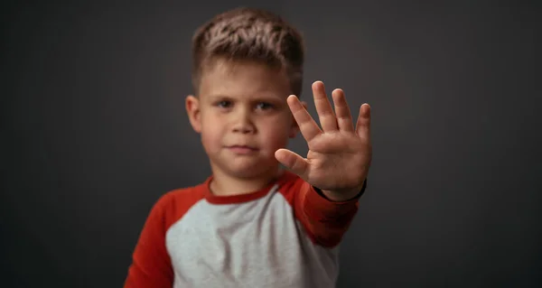 Ragazzino in camicia rossa infelice mostra stop con la mano isolata su sfondo grigio. Emozioni umane, concetto di espressione facciale. Espressioni facciali, emozioni, sentimenti — Foto Stock