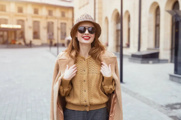 Charmante fille avec un manteau beige d'automne et des lunettes de soleil marchant dans la rue avec un manteau sur les épaules. Photo tonique — Photo