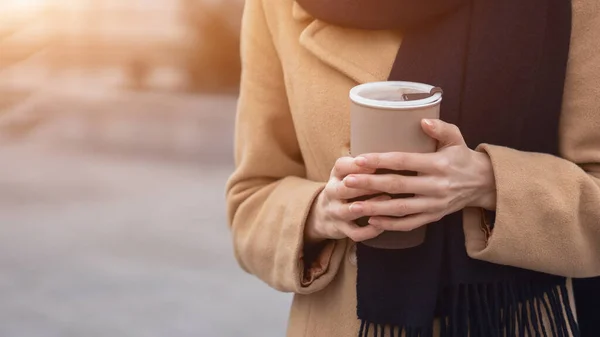 Närbild på kvinnors händer håller en kopp kaffe bär beige rock på gatan kvinnligt mode. Porträtt av stilren ung kvinna i höstrock och röd basker utomhus. Hösttillbehör — Stockfoto