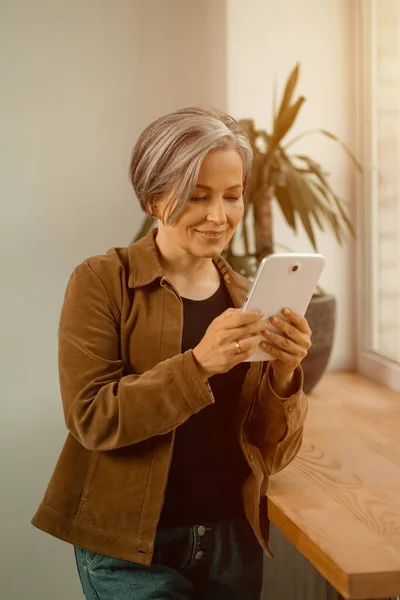 Grey berambut indah wanita dewasa yang memiliki panggilan video menggunakan tablet digital. Pekerja lepas wanita bisnis sedang bernegosiasi melalui link video. Video berwarna — Stok Foto