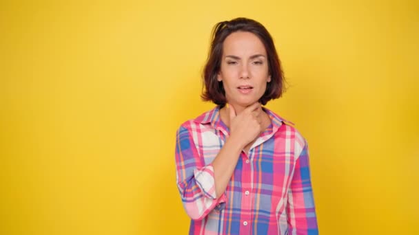 Retrato de uma menina tímida emocional em um fundo amarelo. Mulher encantadora expressando timidez cobrindo rosto com rosto e espreitando para fora. Expressões faciais, emoções, sentimentos. Imagens 4k de alta qualidade — Vídeo de Stock