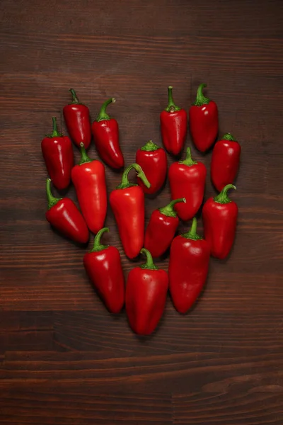 Coração fresco de pimentas ou pimentas e capsicums ou pimentas. Sino doce, páprica, caiena, pimenta de cera húngara, isolado em fundo de mesa de madeira. Foto vertical. Vista superior — Fotografia de Stock