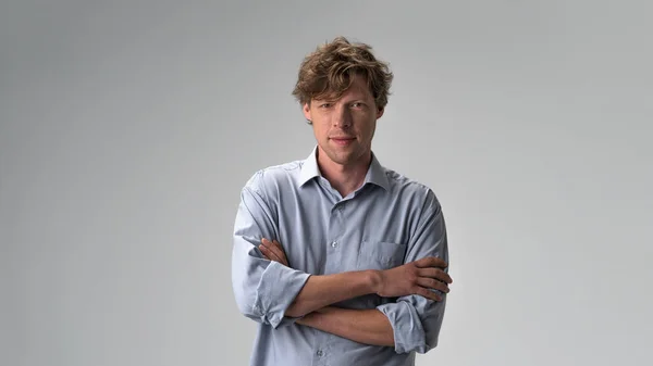 Handsome hipster guy standing with arms folded isolated on light white pastel background. Closeup photo of amazing friendly guy fluffy hairstyle. Studio portrait