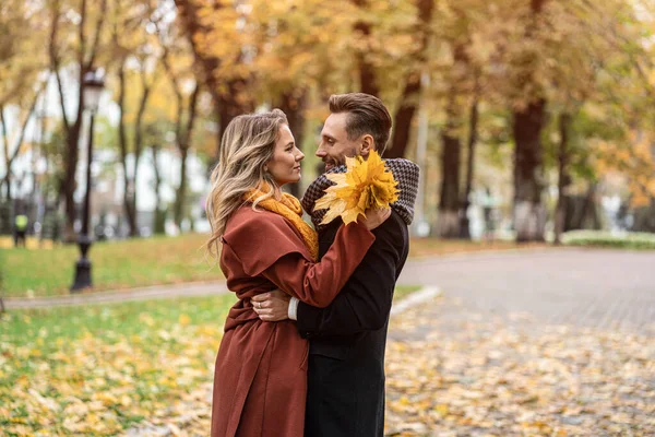 Om ett kyssskott. Maken och en fru kramas leende tittar på varandra i höstparken. Utomhus bild av ett ungt par kär har roligt att ha en kram i en höstpark. — Stockfoto