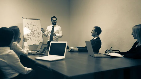 Das getönte Bild des Supervisors, der dem im Besprechungs- oder Konferenzraum sitzenden Team das Planungskonzept zeigt. Geschäftsleute treffen sich im Büro, um eine Idee auszutauschen. Format 16x9 — Stockfoto