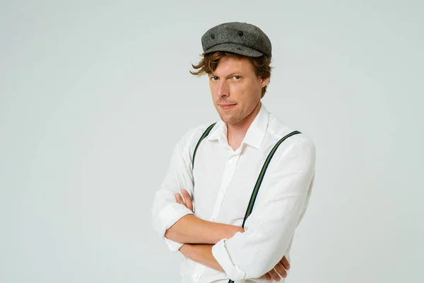 Hipster man posing with hands folded dressed in white shirt and grey wool cap isolated on white background. Copy space at left side — Stockfoto