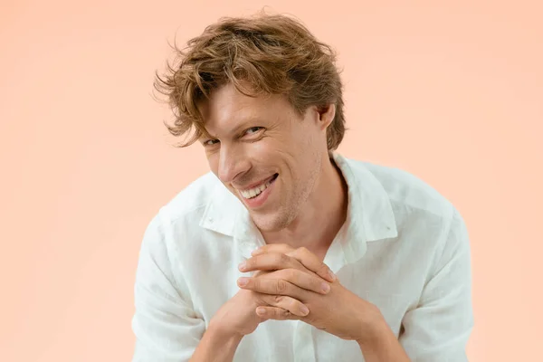 Smiling cheerful handsome man with his hands put together preparing a new important step. Confident man freelancer posing isolated on peach background — Stockfoto