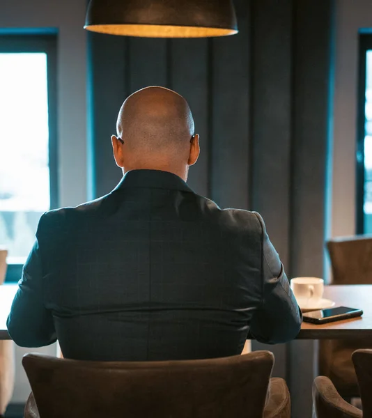 Πίσω όψη του CEO επιχειρηματίας ντυμένος με ακριβό κοστούμι κάθεται στο τραπέζι στο σύγχρονο ακριβό εσωτερικό γραφείο, φαλακρός άνδρας που εργάζονται σε φορητό υπολογιστή. Οριζόντια εικόνα — Φωτογραφία Αρχείου