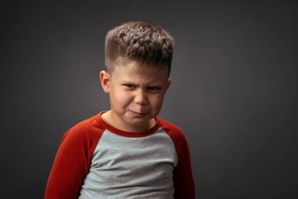 Garçon en colère fronçant les sourcils, montrant avec son visage détestent isolé sur fond gris. Faux sentiments d'enfant. Émotions humaines, concept d'expression faciale. Expressions faciales, émotions, sentiments — Photo