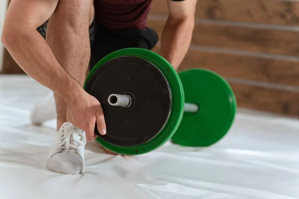 Levantar un arco joven de barra en una rodilla añadiendo o cambiando placas negras y verdes, equipo para el concepto de entrenamiento con pesas. Equipamiento deportivo para entrenamiento. pérdida de peso, concepto de estilo de vida saludable — Foto de Stock