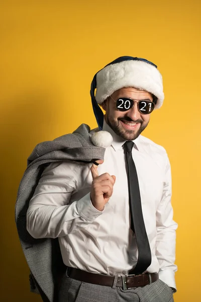 Handsome stylish bearded smiling Santa man wearing blue Santa Claus hat sunglasses and suit, looking at camera isolated on yellow background. Positive emotions, feelings seasonal holidays — Stockfoto