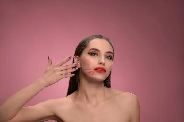 Messed up red lipstick on her face fashion model beautiful woman with long straight hair standing in the studio isolated on dirty pink background. Lips make up concept — Stockfoto