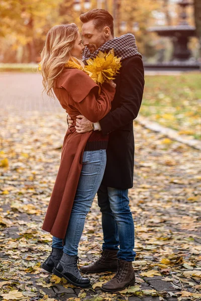 Całowanie młodej pary. Mąż i żona przytulili się, patrząc na siebie w jesiennym parku. Outdoor shot młodej pary zakochanej świetnie się bawią w jesiennym parku — Zdjęcie stockowe