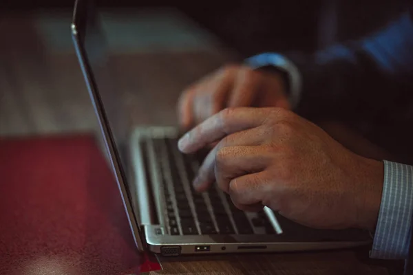 Homem trabalhando em laptop sentado no escritório moderno. Um homem a trabalhar num portátil no escritório. Conceito de negócios e finanças. Imagem tonificada — Fotografia de Stock