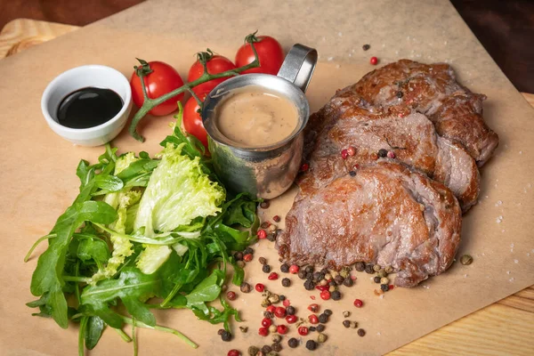 Pork fillets are served with barbecue sauce, soy sauce, cherry tomatoes, lettuce salad with arugula-seeded pepper mixture. Restaurant concept. Restaurant food. Grill concept — Stock Photo, Image
