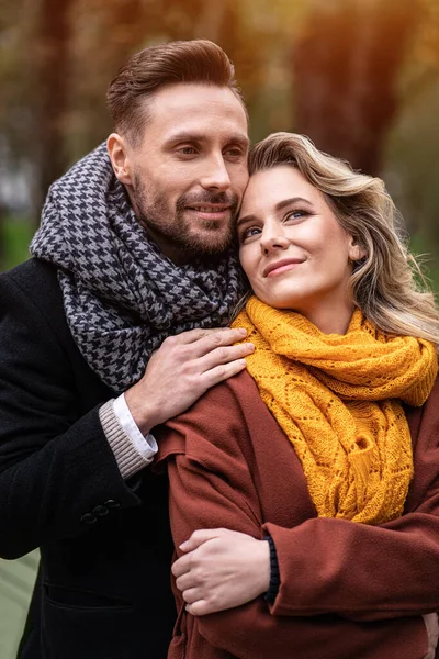 La ternura de una linda pareja. Hombre guapo y una mujer se abrazaron por detrás de la sonrisa mirándose en el parque de otoño. Al aire libre de una joven pareja enamorada pasar un buen rato — Foto de Stock