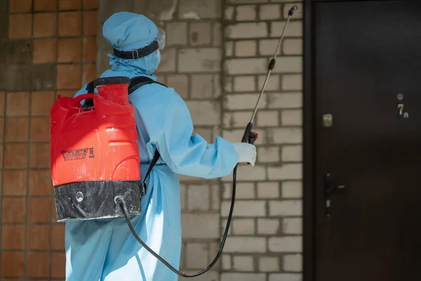 Vista posteriore della donna in tuta protettiva medica che disinfetta la parete esterna dell'edificio. Trattamento medico preventivo di costruzione con antisettico. Ospedale cittadino. maggio, 2020, Brovary, Ucraina — Foto Stock