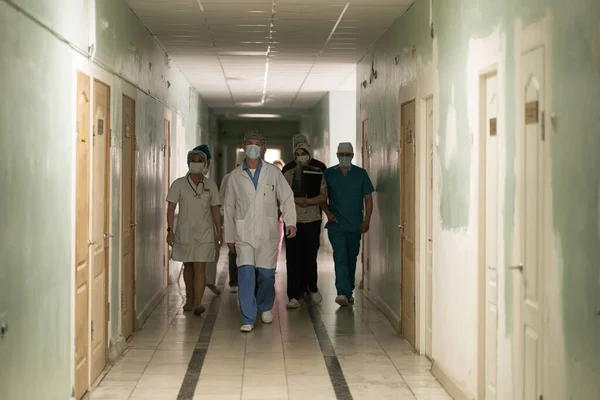 Caminhando ao longo do corredor hospitalar grupo de médicos e enfermeiros. Uma equipe de médicos em uniformes andando ao longo do corredor. Hospital da cidade. Maio, 2020, Brovary, Ucrânia — Fotografia de Stock