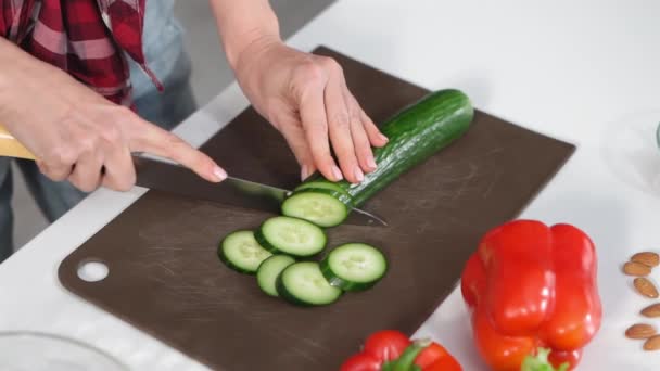 Mujer cortando pepino en rodajas en la mesa cocinando un almuerzo o cena de pie en la cocina. Vida sana de la comida. Estilo de vida saludable. De cerca. Imágenes de FHD — Vídeos de Stock