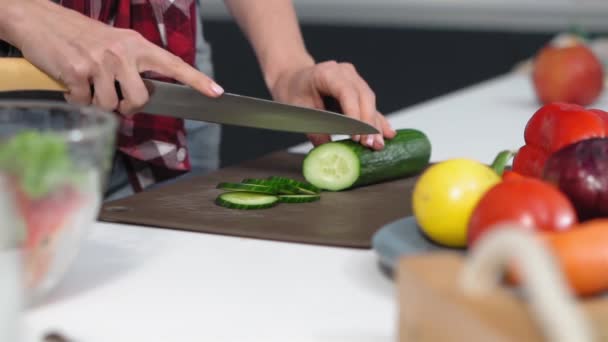 低角度。用细嫩的手在厨房里把黄瓜切在桌上做午饭或晚餐。健康的食物。健康的生活方式靠近点FHD镜头 — 图库视频影像