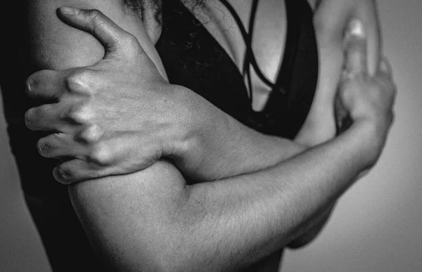 Black and white no face visible. Self-defense, fearful African American girl standing covered with hands in black bare shoulder top isolated on grey background. Human emotions concept — Stock Photo, Image