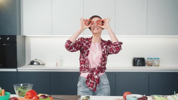 Mulher de cabelo curto em camisa vermelha brincando com alimentos, corte fatias de papel doce enquanto cozinha na cozinha branca. Comida saudável em casa. Alimentação saudável deixando conceito. Imagens de FHD — Vídeo de Stock
