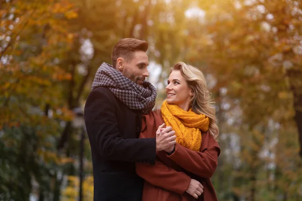 Portret zakochanej pary. Przystojny mężczyzna i kobieta przytulali się od tyłu, patrząc na siebie w jesiennym parku. Zdjęcie młodej zakochanej pary bawiącej się świetnie. Jesienny stonowany obraz — Zdjęcie stockowe