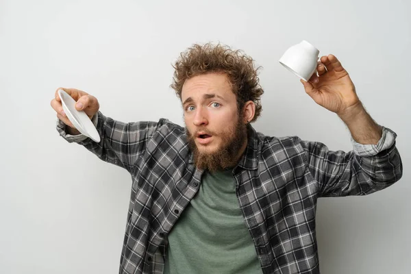 Nessun caffè nella tazza invertita bell'uomo con i capelli ricci e la barba che tiene la tazza, indossando camicia a maniche lunghe a quadri isolata su sfondo bianco. Concetto di crisi e blocco — Foto Stock