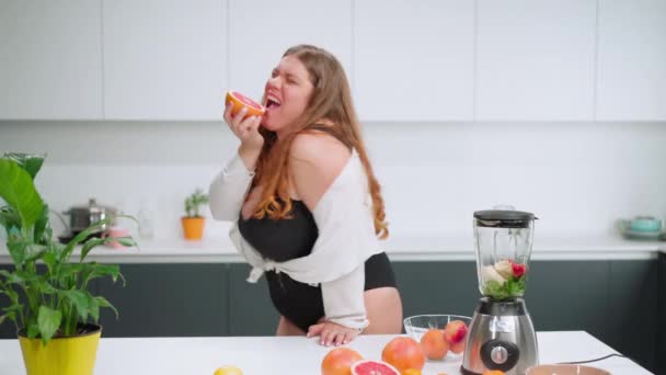 Mujer joven cuerpo curvilíneo feliz con el pelo largo y rubio utilizando licuadora en la cocina moderna, la mezcla de frutas frescas para batido saludable. Concepto de dieta y nutrición. Archivo de alta definición — Vídeos de Stock