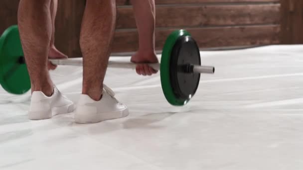 훈련용 스포츠 장비. 역도 선수인 젊은 남자는 체중 훈련 개념을 위한 장비인 검은 색과 녹색의 무게를 쥐기 위해 허리를 구부렸다. 체중 감소, 건강 한 생활 방식의 개념. 4K 동영상 — 비디오