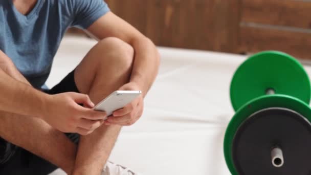 Peralatan olahraga pria untuk pelatihan. Memiliki istirahat pemuda duduk di lantai dengan nada hitam dan hijau barbel kebugaran, peralatan untuk konsep latihan berat badan. Konsep gaya hidup sehat. 4K Footage — Stok Video