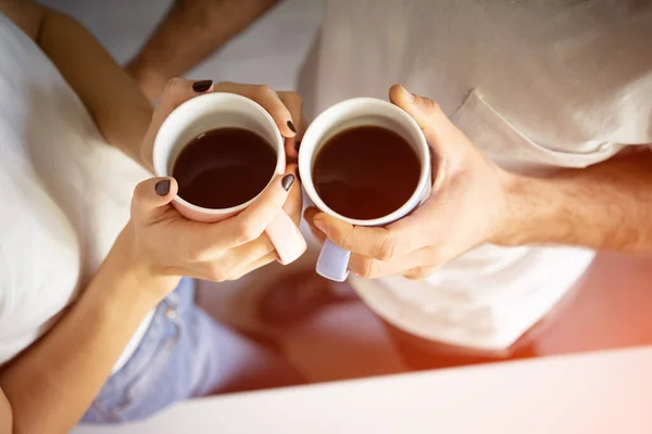 Vue de dessus. Deux mains avec des tasses de café tenant par jeune couple debout le matin sur la cuisine. — Photo