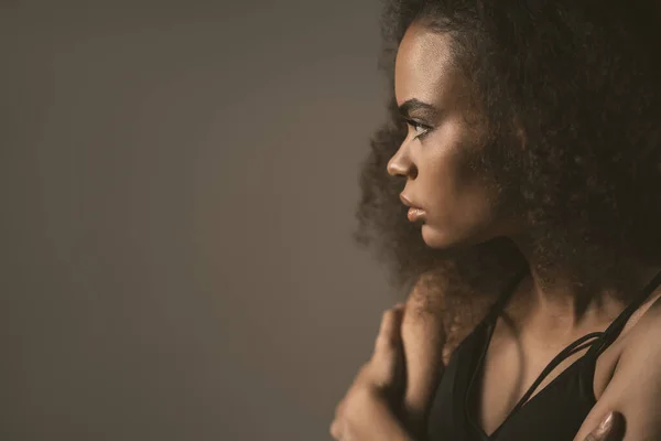 Triste o dopo aver rotto con il fidanzato ragazza afroamericana in piedi in top nero isolato su sfondo grigio. Emozioni umane, concetto di espressione facciale — Foto Stock