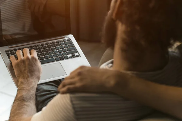 Tiro pelas costas. Trabalhando juntos jovem casal ficar em quarentena em casa com sentado nas poltronas. feliz jovem casal sentado em uma cadeira juntos usando laptop — Fotografia de Stock