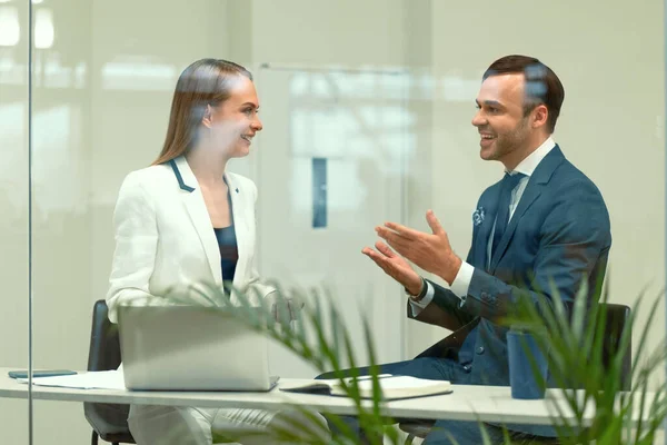 Sorrindo diversos parceiros de negócios jovem homem e mulher discutindo projeto sentado em um moderno encontro brilhante. Bonito jovem empresário e uma mulher cooperando no escritório — Fotografia de Stock