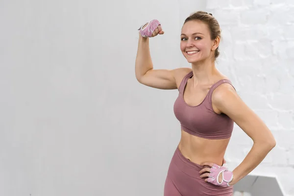 Mulher forte mostrando bíceps de pé vestindo roupa rosa exercitando em casa. Esporte e conceito de recreação. Menina pensativa está gostando com seu processo de treinamento trabalhando duro. conceito de esportes — Fotografia de Stock