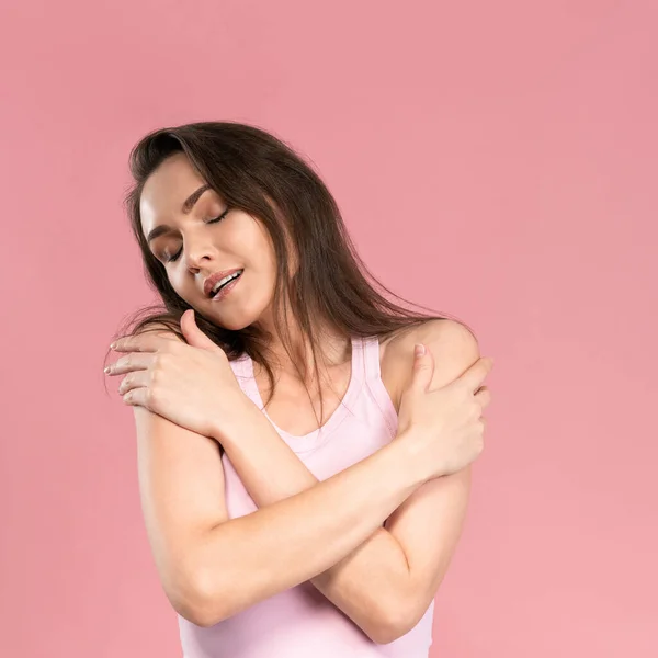 Zarte schöne junge Frau ohne Make-up, die Hände auf der Brust verschränkt, attraktives brünettes Mädchen auf rosa Hintergrund. Schönheits- und Gesundheitskonzept — Stockfoto