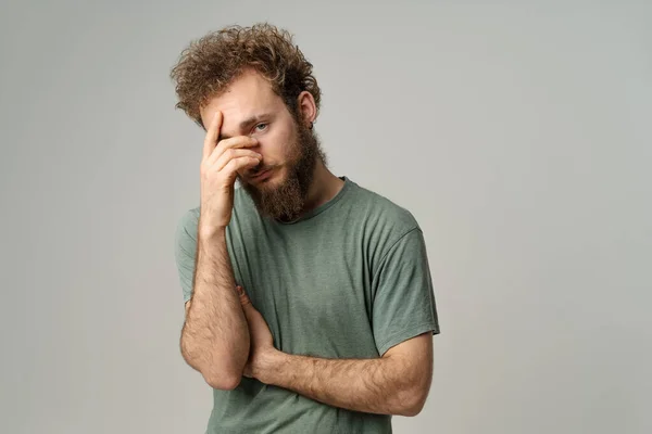 Ashamed or facepalm hiding face young man covered his with hand pry with his eye, curly hair in olive t-shirt isolated on white background. Portrait of ashamed young man —  Fotos de Stock