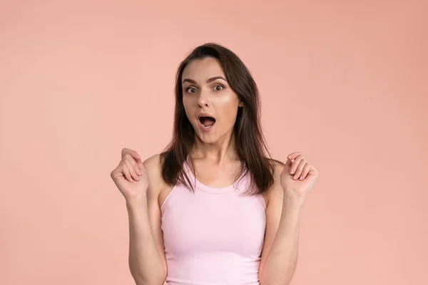 Acting young woman expressing OMG wearing pink t-shirt with hands on her face, excited and joy expression on her face with positive emotions. Facial expressions, emotions, feelings —  Fotos de Stock