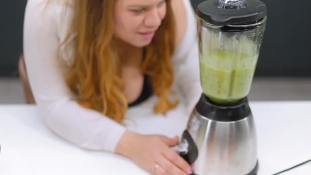 Vista superior. Fazendo fresco mulher smoothie verde com corpo curvilíneo em pé na cozinha moderna. Jovem mulher fazendo suco de desintoxicação saudável feito com o liquidificador em casa. Conceito de dieta e nutrição. FHD — Vídeo de Stock