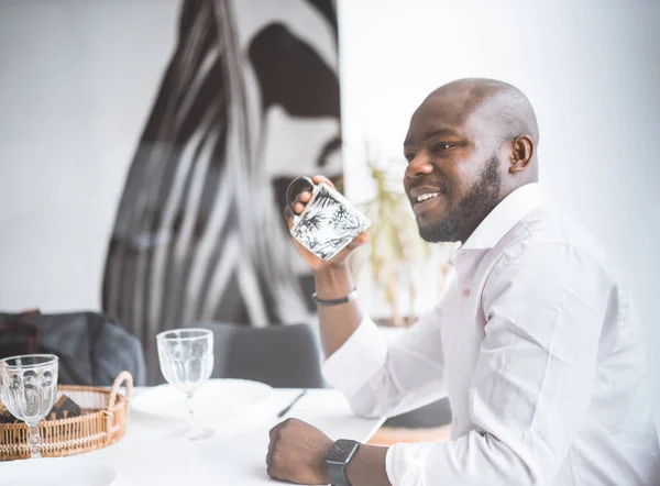 Framgångsrik ung affärsman. African American Man ler medan du sitter vid frukost i lyx lägenhet. Begreppet rikt liv, personlig utveckling — Stockfoto