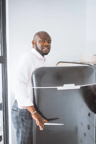 Úspěšný mladý podnikatel. Africký Američan otevře ročník Lednice ve svém bytě. Koncept bohatého života, osobního růstu — Stock fotografie