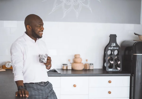 S pozdravem v kuchyni. Šťastný Afroameričan s pohárem vypadá pryč. Setkání přátel úspěšného podnikatele doma — Stock fotografie