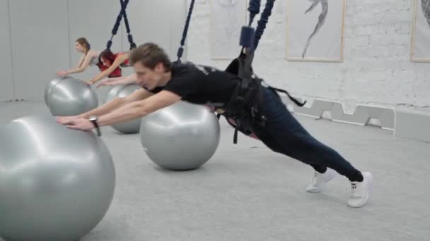 Οι δυνατές γιανγκ κάνουν γυμναστική σε μπάντζο. Προπονητής δείχνει κατεύθυνση στην μπάλα ενίσχυση των μυών του πυρήνα. — Αρχείο Βίντεο